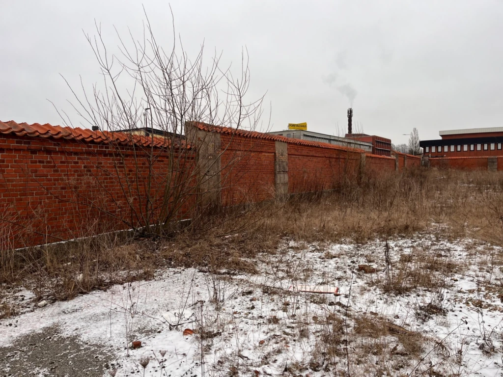 Foto över stenatomten i eslövs kommun. Stenmur av tegel i bakgrunden